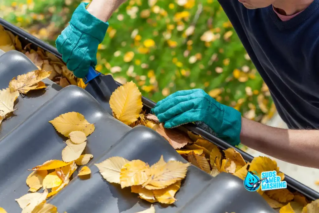 Gutter cleaning Pennsylvania — clearing clogged autumn leaves from roof gutter to prevent water damage